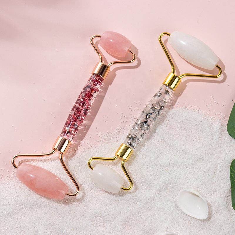 lireth. rose quartz and white jade rollers on pink sand with a shell